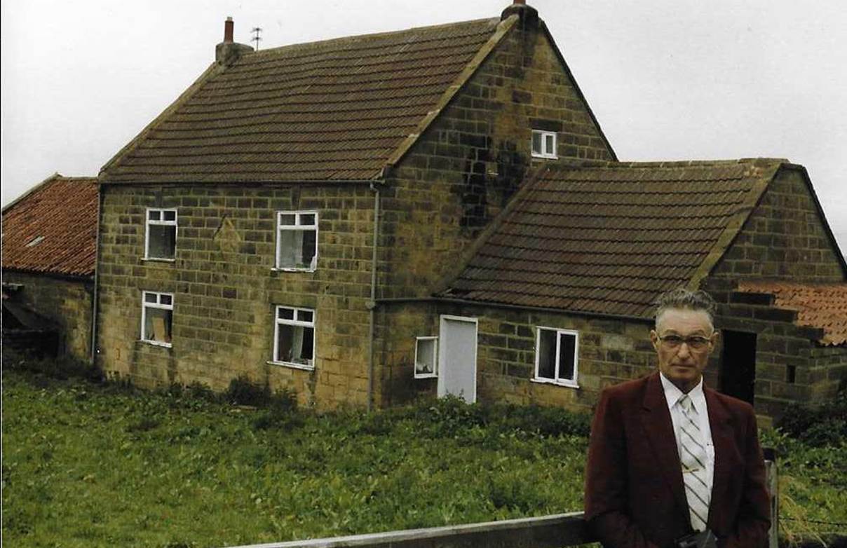 An old brick building with grass in front of a house

Description automatically generated